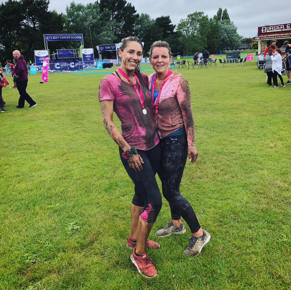 A photograph of two Cold Banana employees wearing medals and covered in mud having completed a tough mudder.