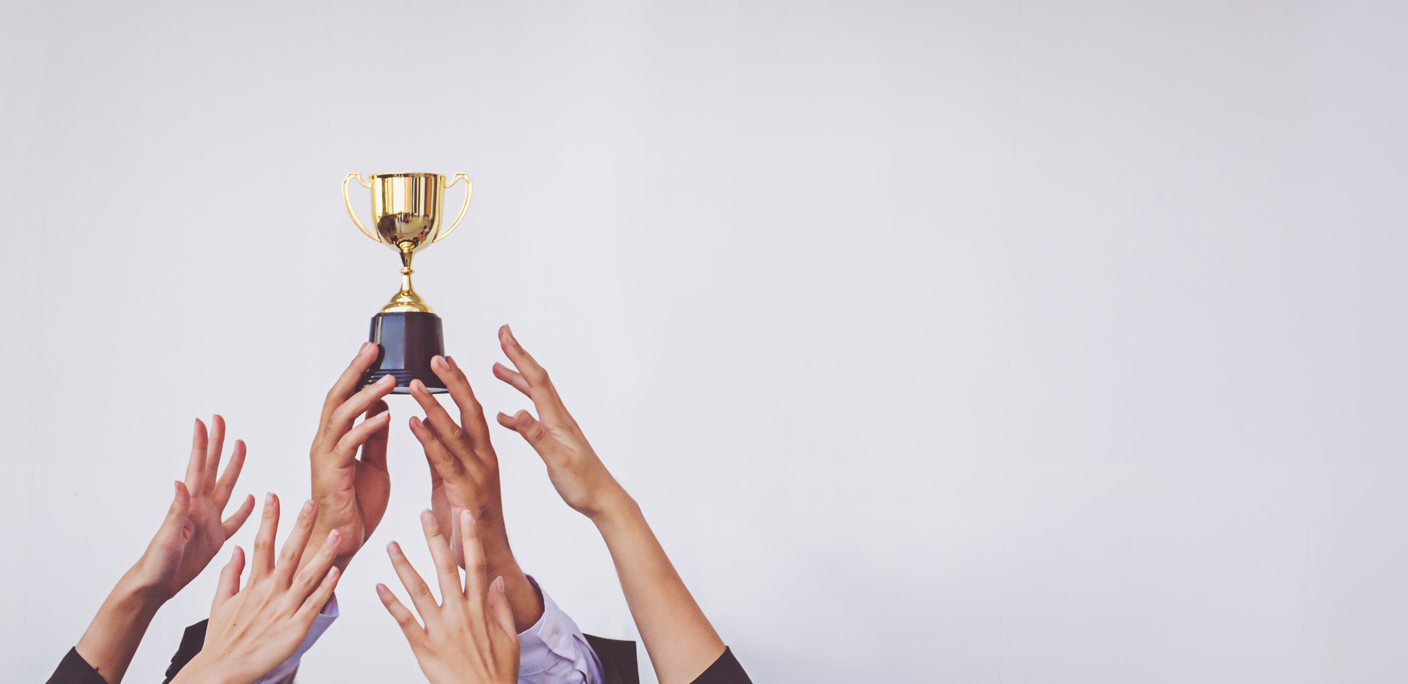 Hands reaching for a golden trophy held aloft