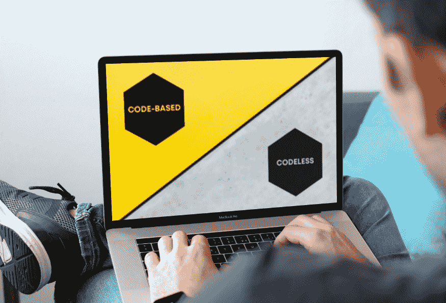 A man on a laptop looking at a graphic. The graphic shows two hexagons with "Code-based" in one and "Codeless" in another.