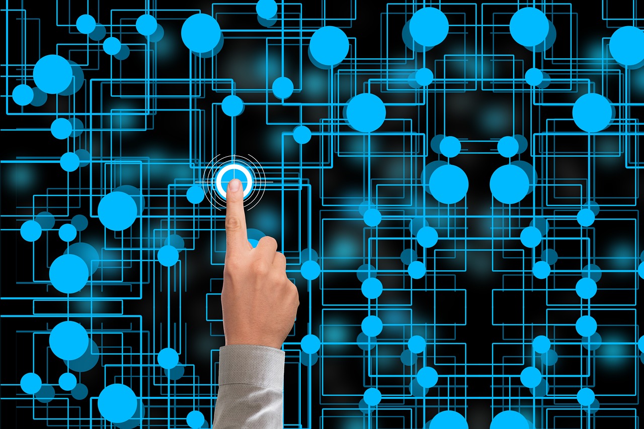 A hand pressing on a etwork of blue nodes, with the pressed node producing outward ripples.