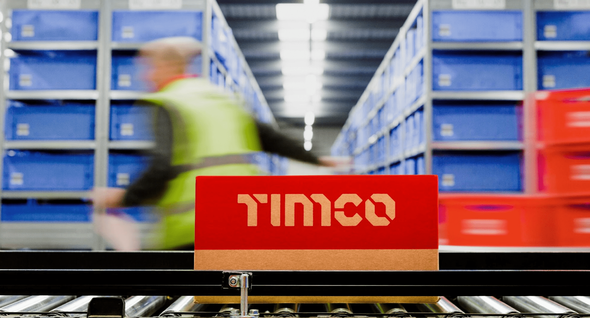 A TIMCO box travelling through a warehouse on a conveyer belt.