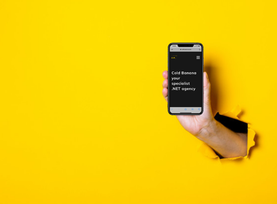 A hand holding a smartphone with the Cold Banana website on it, bursting through a yellow wall