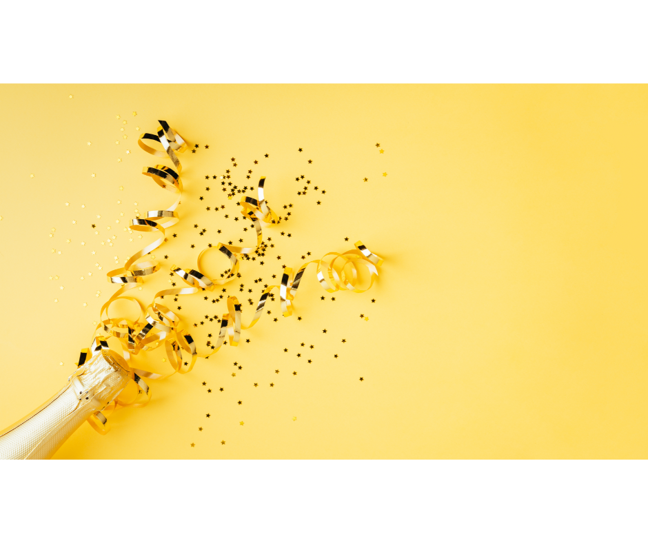 Party streamers and confetti popping out of a champagne bottle in celebration.