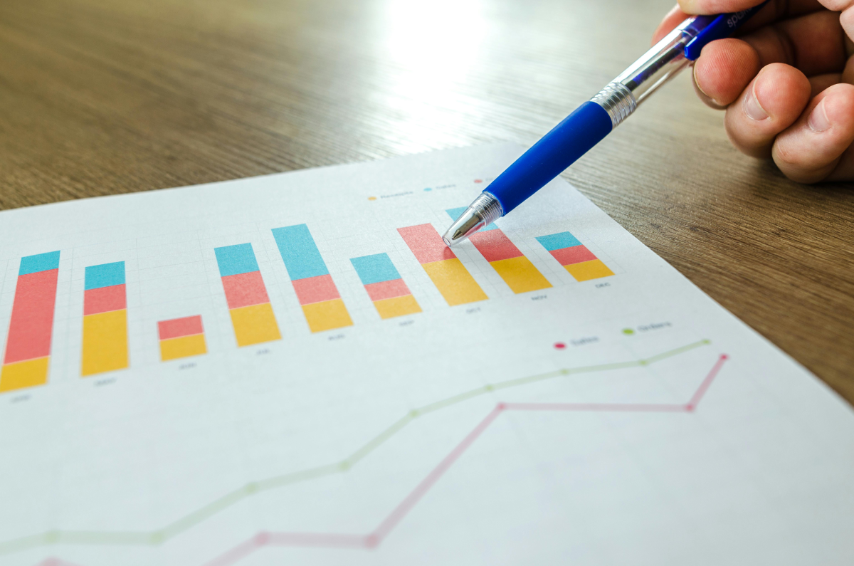 A person using a blue pen to point at a section of a bar graph