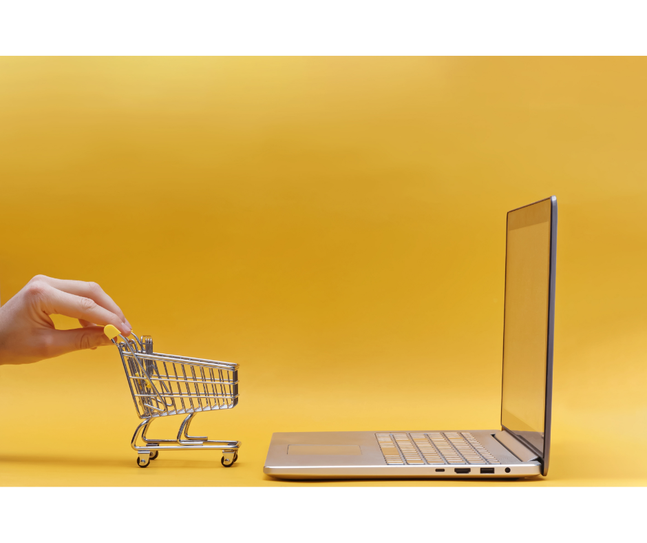 A person pushing a toy trolley in front of an open laptop.
