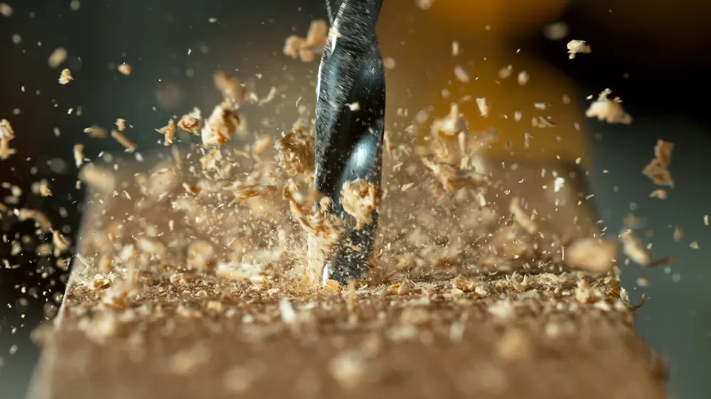 A drill working through a timber beam