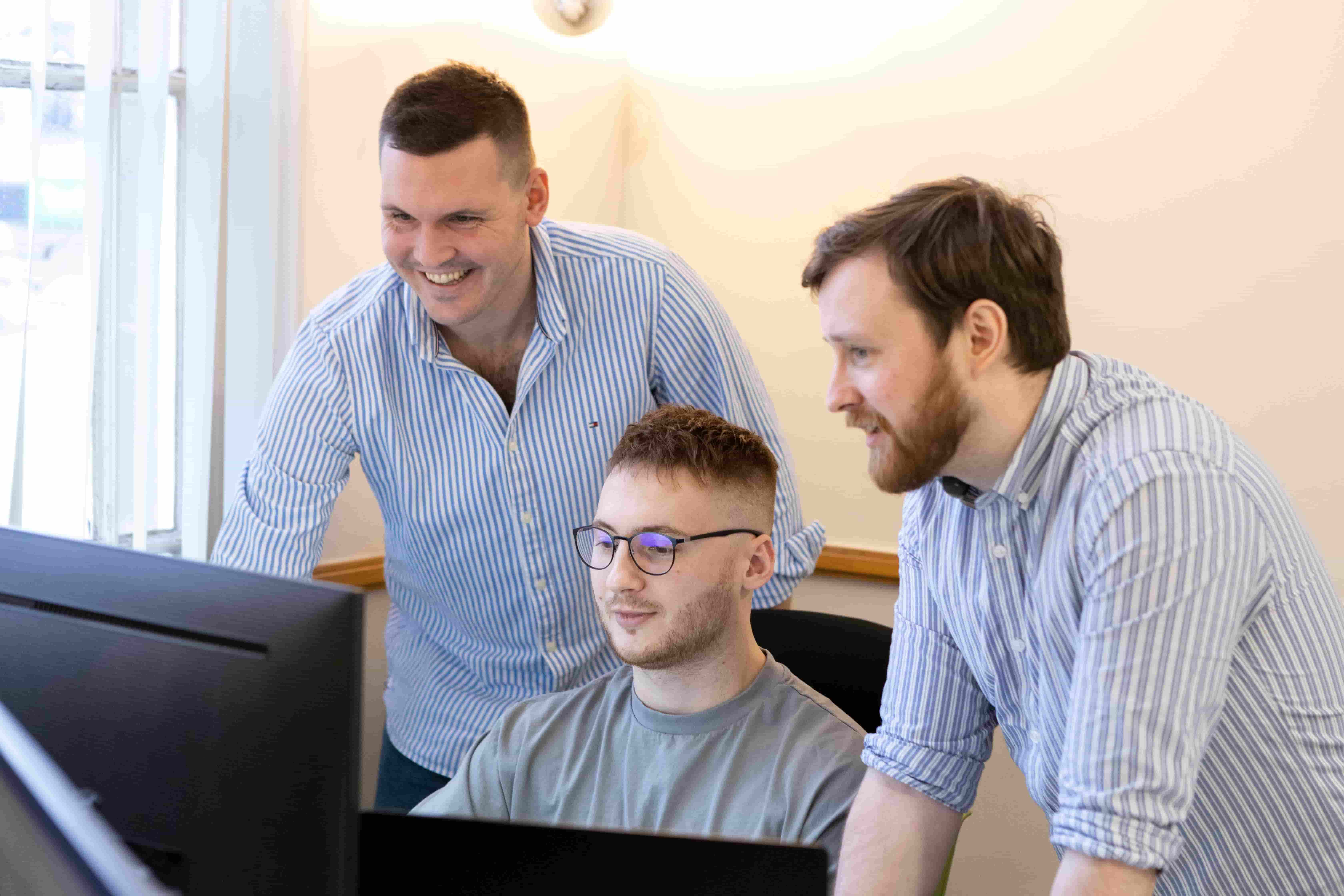 Three workers at a computer solving a problem.