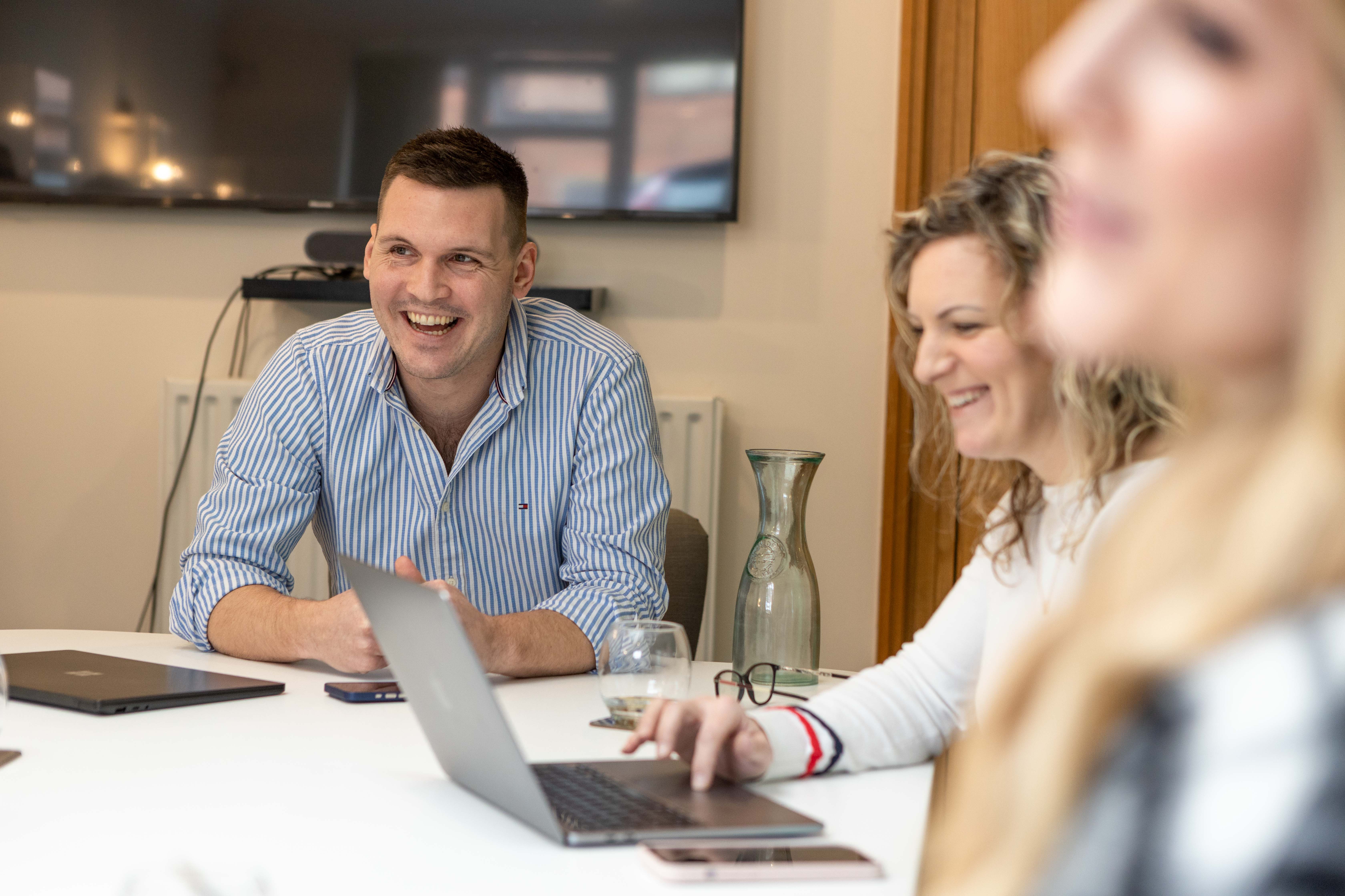 Three Cold Banana employees in a meeting room laughing.
