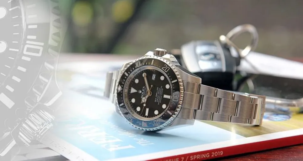 A Rolex on a magazine with a set of car keys in the background
