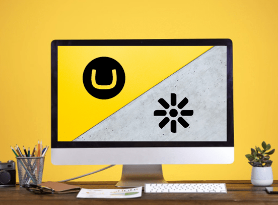 Umbraco vs Kentico graphic on a desktop, with desk paraphernalia surrounding the monitor