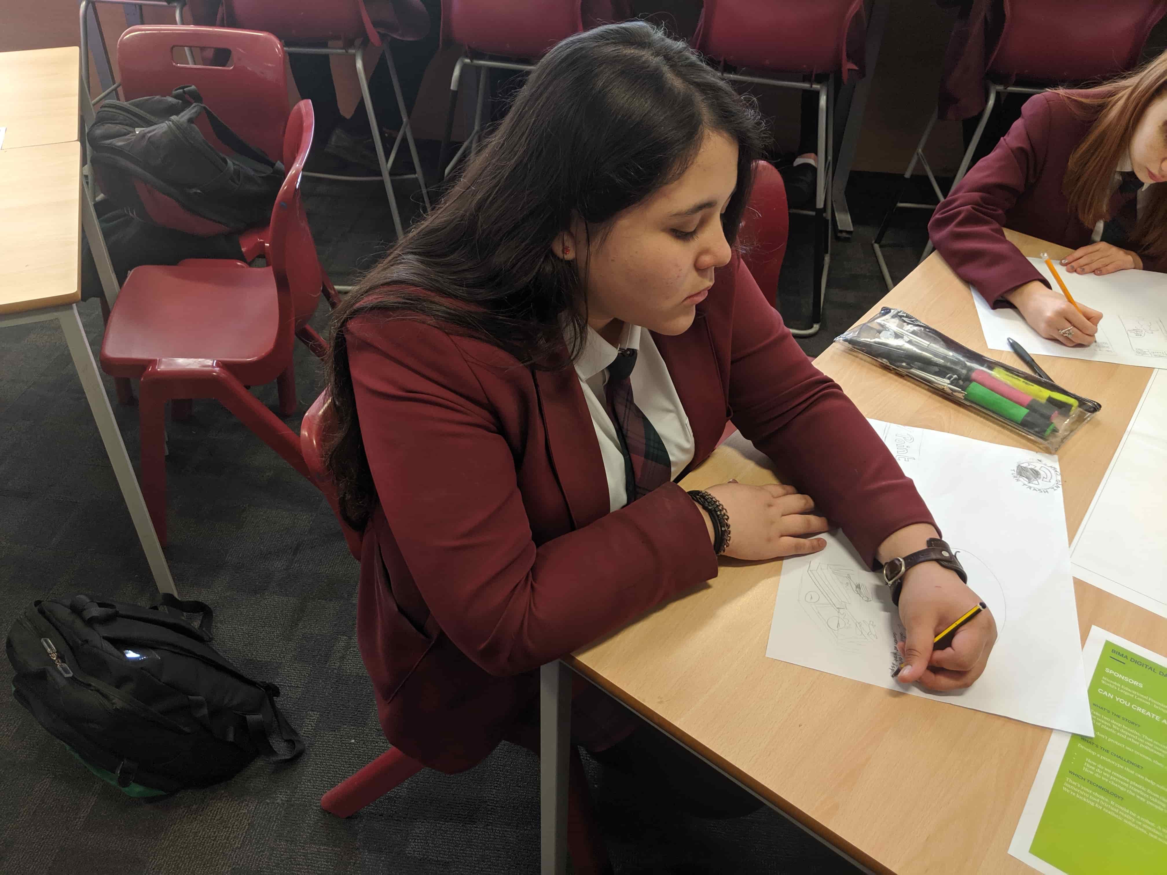 A school child drawing a design on paper for the poster portion of BIMA Digital Day 2019.