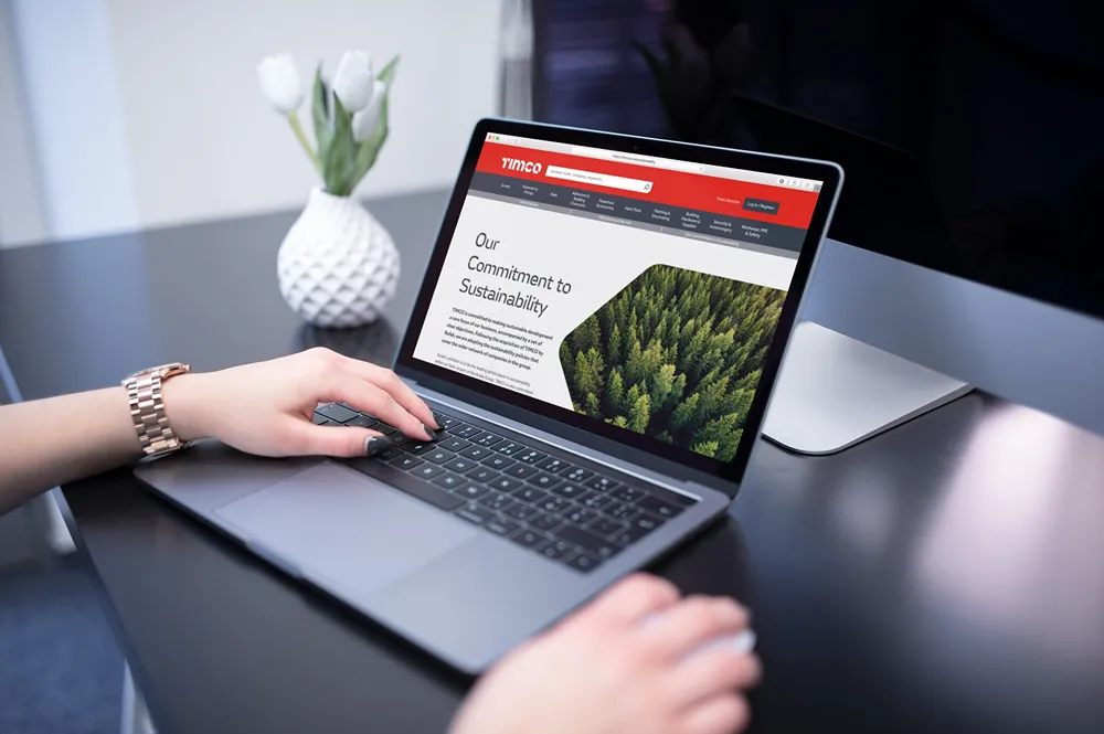 TIMCO's sustainability page displayed on a laptop, with a forest image and editorial content.