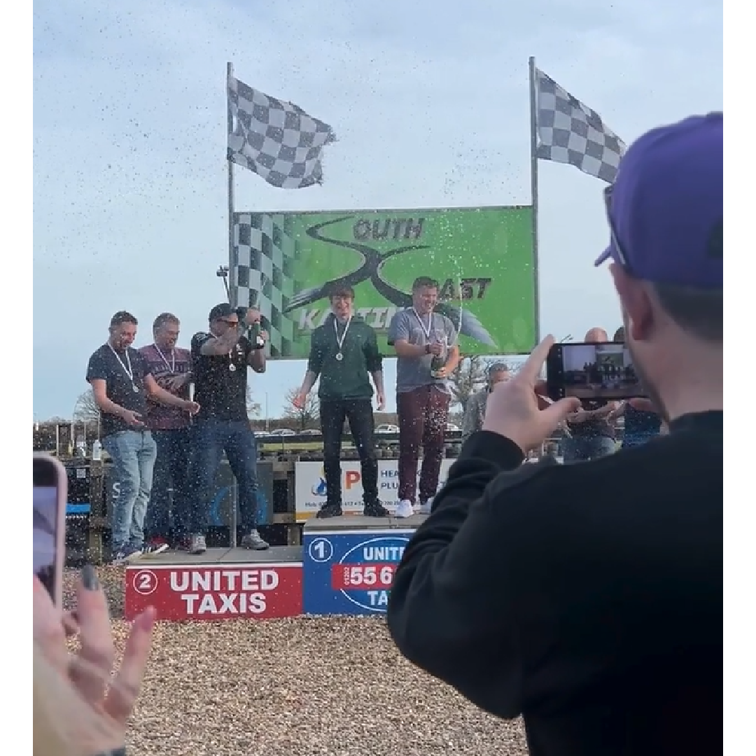 The Cold Banana Agency Grand Prix 2025 racers celebrating their win by popping a champagne bottle on the podium.