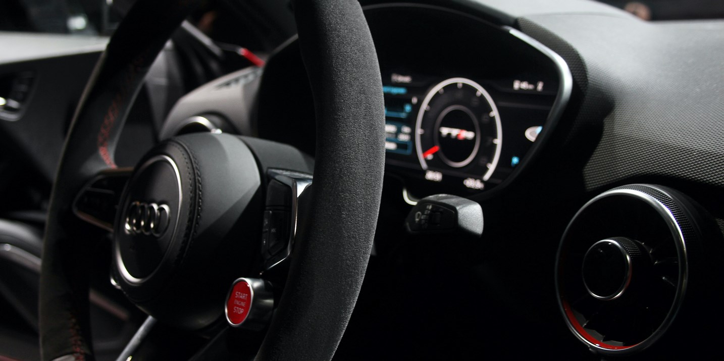 Interior view of a car, with the steering wheel and dashboard visible