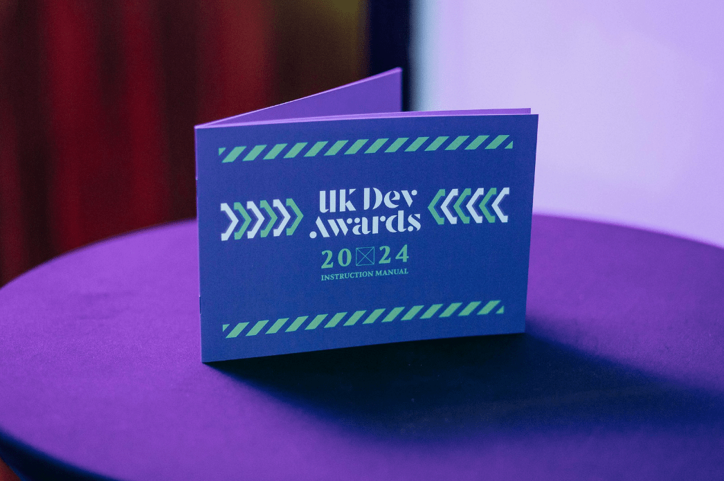A photo of the UK Dev Awards Instruction Manual on a table with a purple tablecloth.