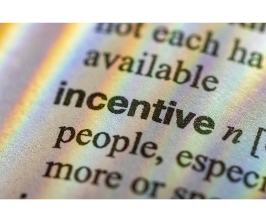 A dictionary with the word "incentive" present with refracted light forming a rainbow across the page.