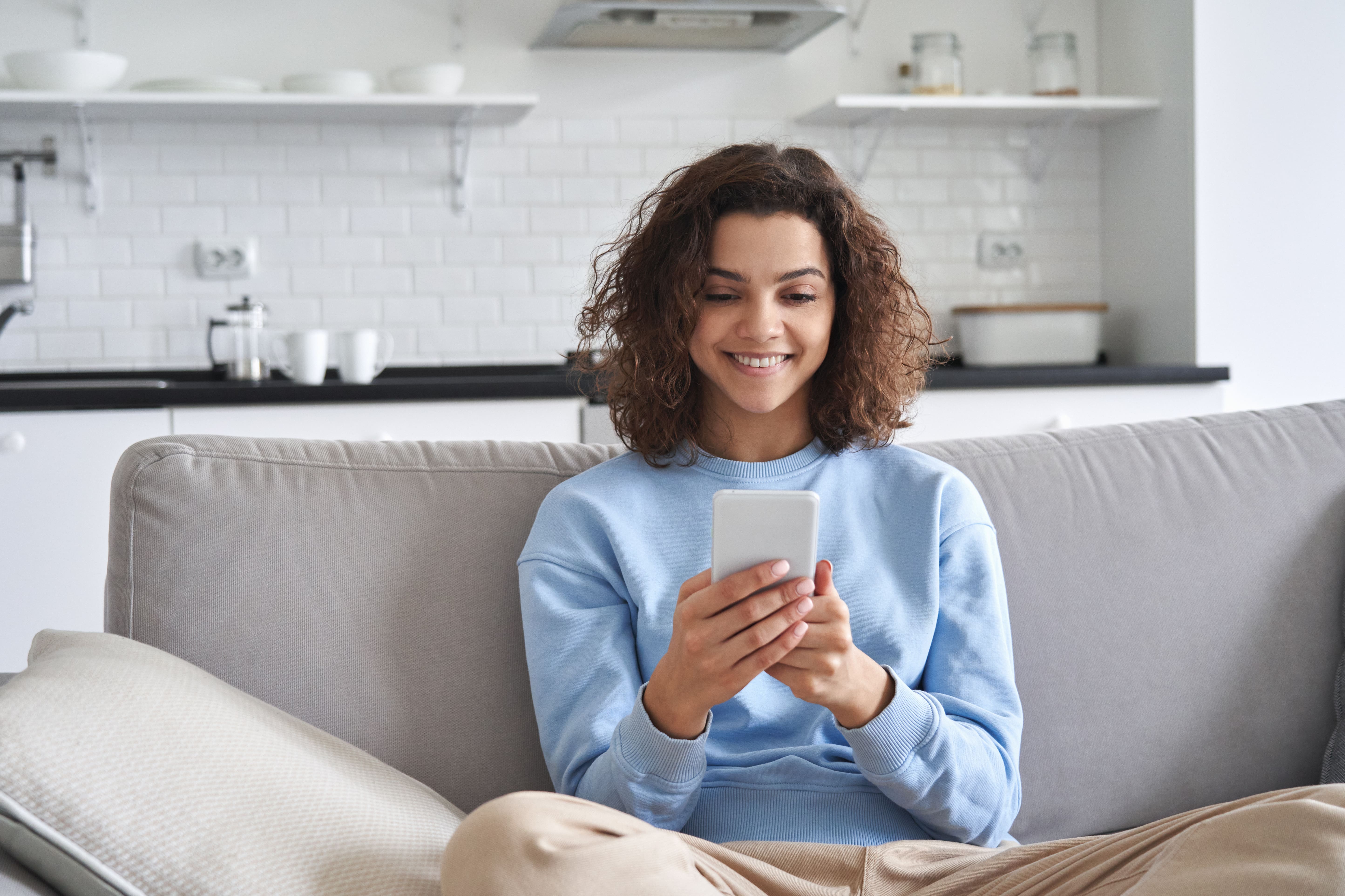 Woman on her smartphone whilst in her living room.