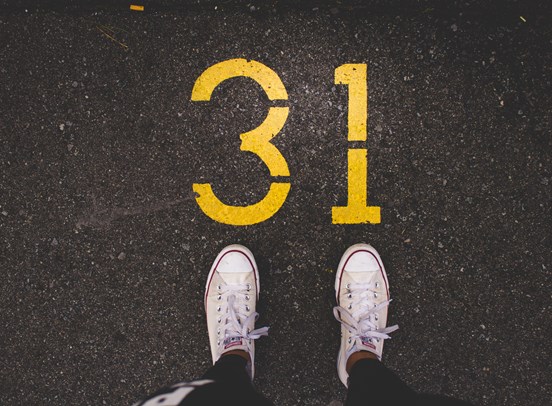 A POV photograph of a person looking down at the number 31 in yellow road paint on the ground.